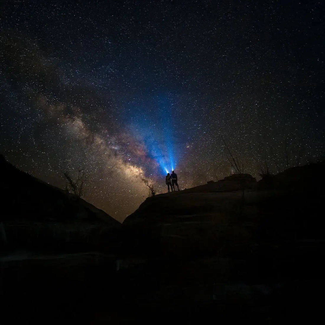 Personen die mit LED Taschenlampen gen Nachthimmel leuchten.